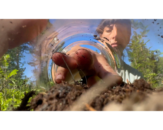 Person reaching into a jar with soil