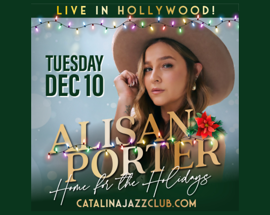 Singer from the Voice Alisan Porter with cowboy hat on with holiday lights in the background
