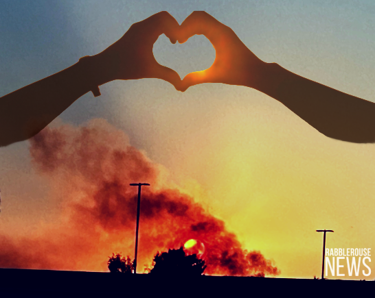 Image of hands forming a heart above smoke from the Kenneth Fire rising over the sun as it sets on January 9, 2025
