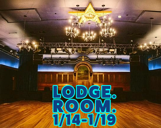 Concert auditorium with a hardwood floor in front of the stage. A Star shaped chandelier hangs from the ceiling as do stage lighting grids.