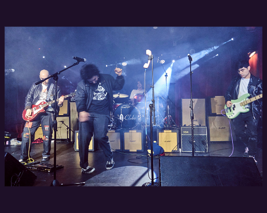Grunge Punk Band Plays with two guitar players, a singer center stage backed by a drummer