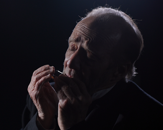 An man plays a french harp on stage in a post-civil war play