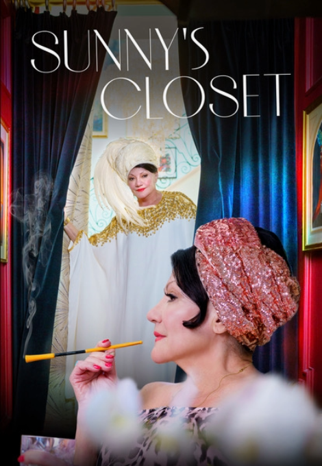 A glamorous woman with dark hair wears a turban and smokes a cigarette on a long cigarette holder