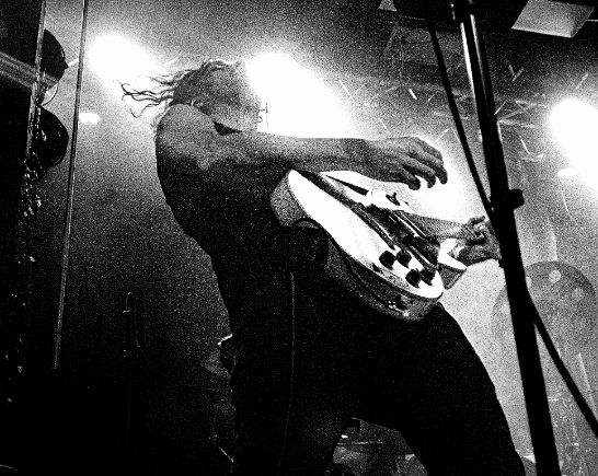 man playing guitar onstage with back lighting