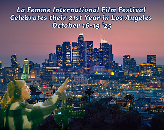 A female filmmaker with a camera points toward the Los Angeles downtown skyline at night