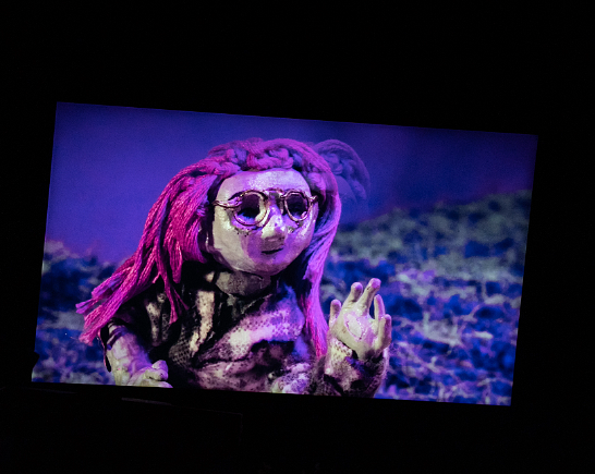A stop motion animated image of a girl with wire rim glasses and purple hair