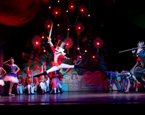 Performance of the Nutcracker with ballerina's at attention as the Nutcracker leaps airborne centerstage lifting his sword aloft