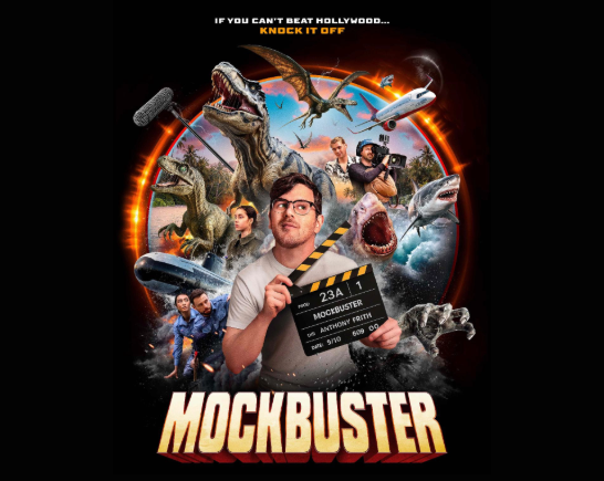 A man wearing glasses holds a slate and it surrounded by characters from hollywood blockbuster film characters