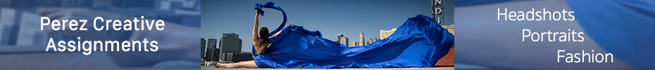 A woman in a flowing cobalt blue dress with a flowing train stretches with arms above her head. Downtown Los Angeles in the background beneath the blue California sky