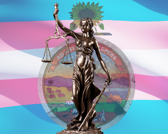 A transgender flag is in the background with a cracked and fading seal of the state of Kansas. In the center foreground stands a bold statue of Lady Justice, Justitia