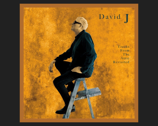 Musician David J wears black as he sits on a stool