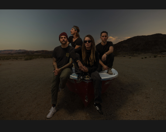 Music artists Cascades stand in twilight with Los Angeles mountains behind them in the shadows and beauty of a California sky