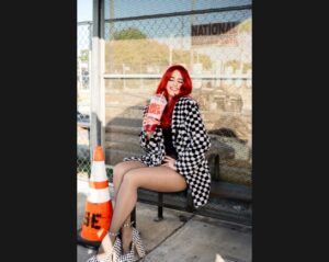 Monique Powell of SAVE FERRIS sits on a bench drinking a Big Gulp