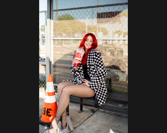 Monique Powell of SAVE FERRIS sits on a bench drinking a Big Gulp