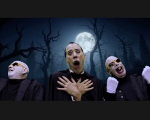 Three Vampires beneath the full moon with dark bare trees in the background